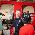 Photo of a firefighter showing off a fire truck